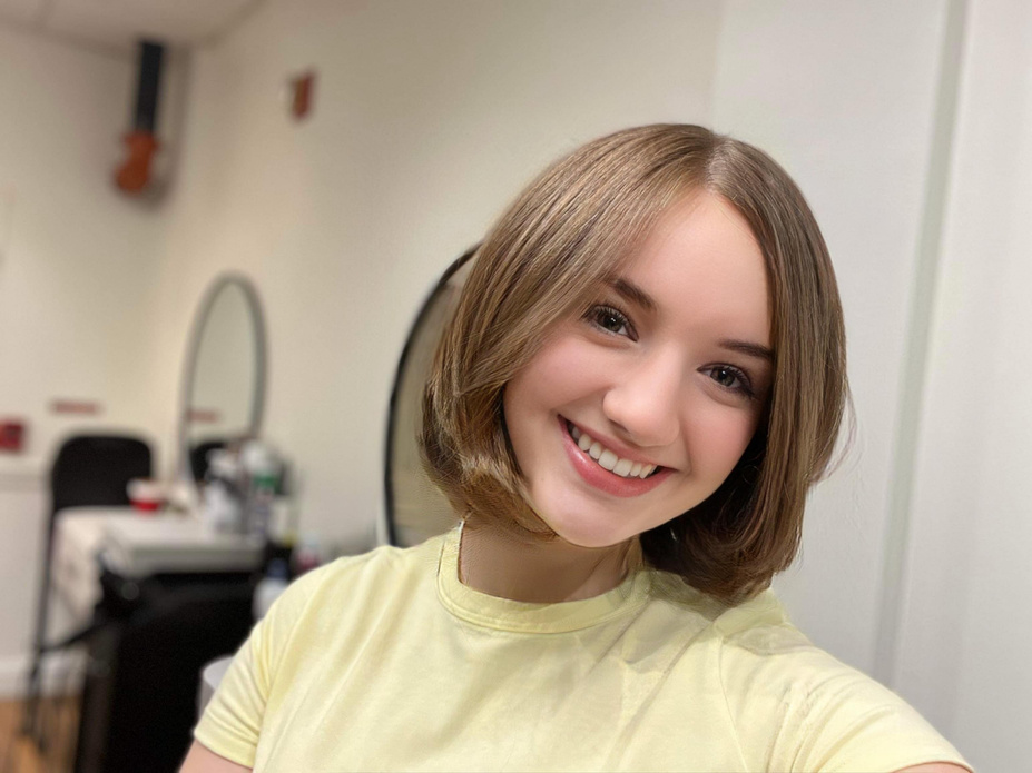 a teenager Rocking a short fabulous haircut, she in a yellow shirt taking a selfie