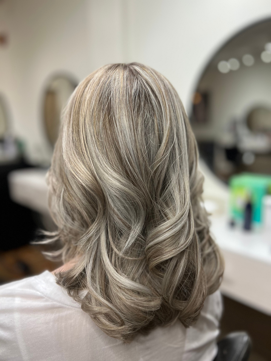 the back of head with beautiful dimensional blonde with highlight and lowlights throughout. She has beautiful curls the make the color pop! 
